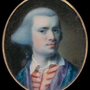 May include: Oval portrait miniature of a man with powdered blue hair, wearing a blue coat with a purple collar and a red and white vest. The portrait is set in a gold frame against a black background. The man has a pale complexion and is looking forward.