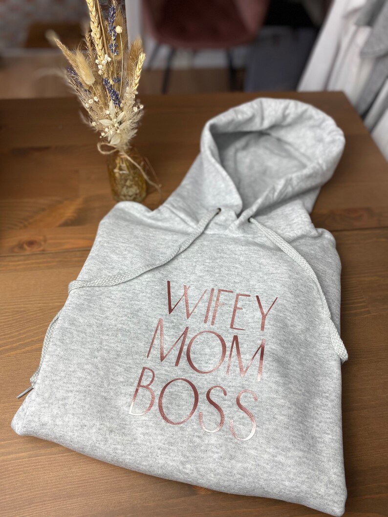 May include: Gray hooded sweatshirt with the text "WIFEY MOM BOSS" printed in rose gold.