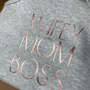 May include: Gray hooded sweatshirt with the text "WIFEY MOM BOSS" in rose gold foil lettering.