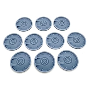 May include: Ten grey, circular miniature bases are displayed. Each base has a central design with an 'X' shape and surrounding details. These bases are designed for tabletop gaming and miniature figures.