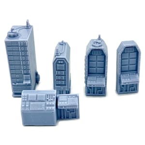 May include: A set of light blue miniature sci-fi structures, including tall rectangular buildings with multiple levels and control panels, and smaller control consoles. The pieces have detailed textures and are designed for tabletop gaming or model building.