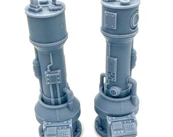 May include: Two gray, cylindrical miniature models with detailed industrial designs. Each model features a rounded base, a central column with pipes and panels, and a top section with various protrusions. The models are likely for a tabletop game or model display.