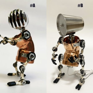 May include: Two robot figures made of metal and copper. The robot on the left has a silver microphone head and the robot on the right has a silver cup head. Both robots have copper bodies and silver joints.