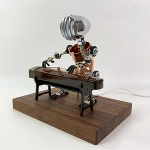 May include: A steampunk-style robot made of metal and wood plays a traditional Chinese zither, or guzheng, on a wooden base.