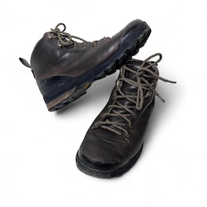 May include: Two brown leather hiking boots with dark soles and matching laces. The boots are worn and show signs of use. The boots are designed for outdoor activities and rugged terrain.