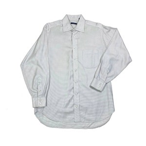 May include: A white long-sleeved button-down shirt with a fine checkered pattern. The shirt has a standard collar and a single chest pocket.