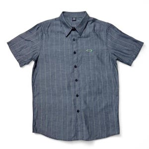 May include: A short-sleeved, button-down shirt in a dark gray color with vertical white stripes. The shirt has a pointed collar and a small green logo on the chest. The shirt is buttoned up and appears to be made of a lightweight fabric.