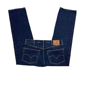 Puede incluir: Un par de pantalones vaqueros de mezclilla azul oscuro con un parche de cuero marrón que dice "Levi's" en la parte posterior.