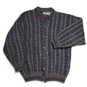 May include: A gray, button-down cardigan sweater with a textured pattern. The sweater has a round neckline and ribbed cuffs and hem with red and navy blue stripes. The buttons are brown. The sweater is made of a thick knit material.