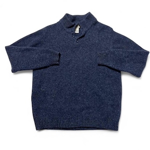 May include: A navy blue sweater with a mock neck collar and three buttons. The long-sleeved sweater has ribbed cuffs and a textured knit. The sweater is laid flat on a white surface.