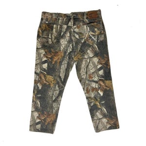 May include: Camouflage print jeans with a brown leather patch on the back waistband. The jeans are a light brown, dark brown, and green colour.
