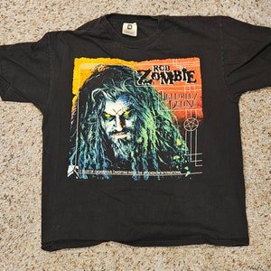 Könnte beinhalten: Schwarzes T-Shirt mit einem Aufdruck des Albumcovers von Rob Zombies Hellbilly Deluxe. Der Aufdruck zeigt eine Nahaufnahme von Rob Zombies Gesicht mit einem Pentagramm und dem Albumtitel.