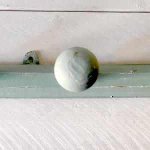 Può includere: Un appendiabiti in legno blu chiaro con tre pomelli rotondi. L'appendiabiti è montato su una parete bianca.