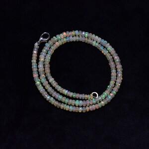 May include: A white opal beaded necklace with a silver clasp. The necklace is made of small, round beads that are iridescent and have a rainbow sheen.