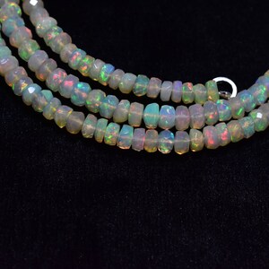May include: A strand of white opal beads with a slight iridescent sheen. The beads are faceted and have a slightly irregular shape.