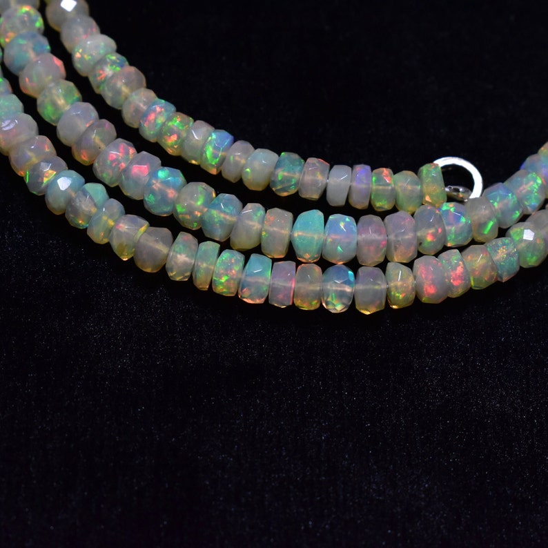 May include: A strand of white opal beads with a slight iridescent sheen. The beads are faceted and have a slightly irregular shape.