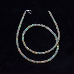 May include: A white opal beaded necklace with a silver clasp. The necklace is made of small, round beads that are strung together on a silver chain. The necklace is approximately 18 inches long.