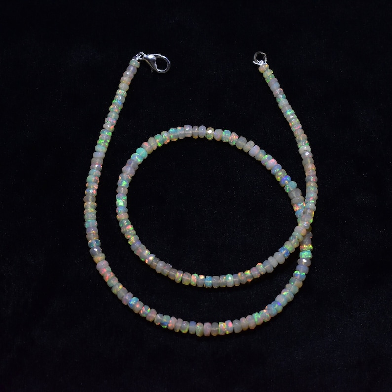 May include: A white opal beaded necklace with a silver clasp. The necklace is made of small, round beads that are strung together on a silver chain. The necklace is approximately 18 inches long.