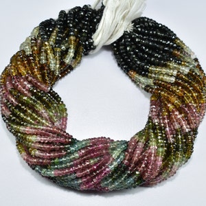 May include: A strand of multi-coloured tourmaline beads. The beads are faceted and have a variety of colours, including green, pink, brown, and black. The beads are strung on a white thread.