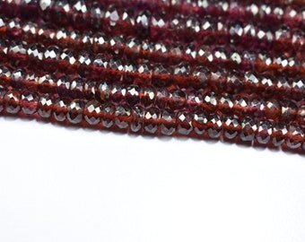 May include: A strand of faceted garnet beads in a deep red color. The beads are round and have a smooth, polished finish.