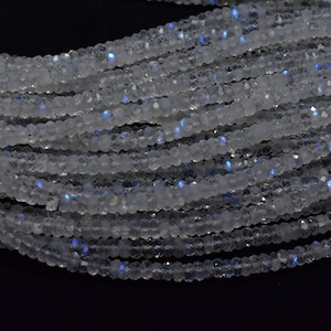 May include: A strand of white moonstone beads with iridescent blue flashes. The beads are faceted and have a smooth, polished finish.