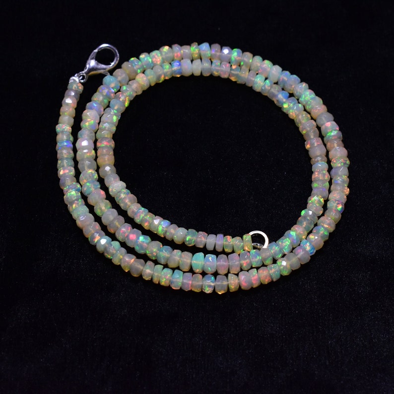 May include: A strand of white opal beads with iridescent rainbow colors. The beads are faceted and have a slightly irregular shape. The necklace is made of two strands of beads and has a silver clasp.