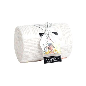 May include: A roll of white fabric with a pink and green floral print. The fabric is wrapped in a white ribbon with a black and white label that says "moda fabrics + supplies".