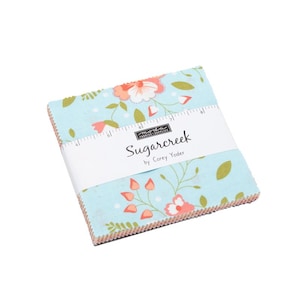 May include: A stack of fabric squares with a floral pattern in shades of blue, coral, and green. The fabric is wrapped with a white band that reads "Sugarcreek by Corey Yoder."