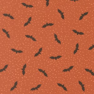 May include: A fabric pattern featuring a burnt orange background with a repeating print of small, dark brown bats scattered across the surface, interspersed with tiny, light-colored speckles that create a textured, dotted appearance throughout.