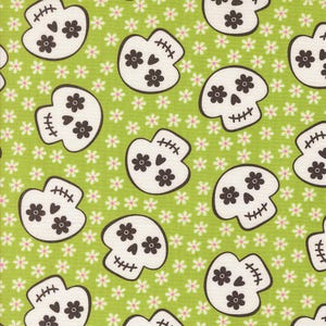 May include: A repeating pattern of white skull shapes with brown floral accents and stitched details. The skulls are set against a light green background dotted with small white and pink flowers, creating a whimsical, festive design.