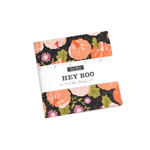May include: A black fabric with a white and orange pumpkin print. The fabric has a white label that says "HEY BOO" by "Lella Boutique".