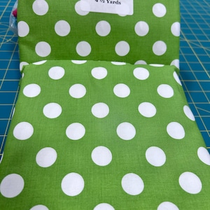May include: Green fabric with white polka dots. The fabric is folded in half and a label reads "4 1/2 Yards".