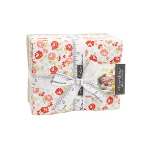 May include: A stack of fabric squares with a floral pattern in shades of pink, red, and green on a white background. The fabric is tied with a white ribbon and a measuring tape. The fabric squares are labeled "moda fabrics supplies".