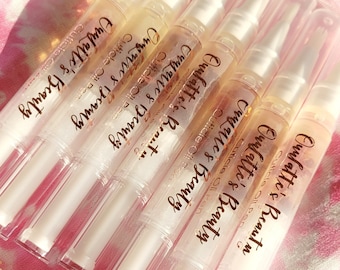 May include: A set of eight clear plastic cuticle oil pens with gold lettering that reads "Ouulatte's Beauty Cuticle Oil Pen".