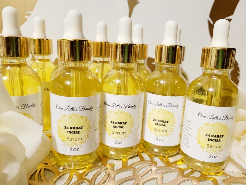 K&ouml;nnte beinhalten: Eine Sammlung klarer Glasflaschen, gef&uuml;llt mit einer goldenen Fl&uuml;ssigkeit, jede mit einem wei&szlig;en Etikett mit der Aufschrift "24 KARAT FACIAL Serum" und "2 OZ". Die Flaschen haben goldfarbene Kappen und wei&szlig;e Tropfer. Der Markenname "Onu Latte's Beauty" ist ebenfalls sichtbar.