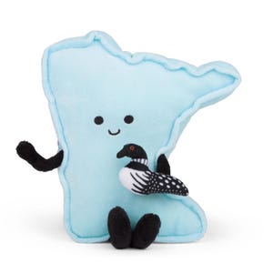 Può includere: Un peluche azzurro a forma dello stato del Minnesota, caratterizzato da un semplice viso ricamato con due occhi neri e un piccolo sorriso. Il peluche ha braccia e gambe nere e tiene in mano una piccola e dettagliata figura di strolaga bianca e nera.