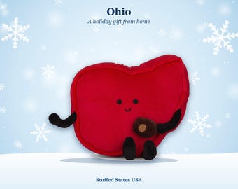 May include: A red plush toy shaped like the state of Ohio with a smiling face, black arms, and black legs. The toy holds a small brown nut. Above the toy, the text reads Ohio A holiday gift from home. Below, the text reads Stuffed States USA.