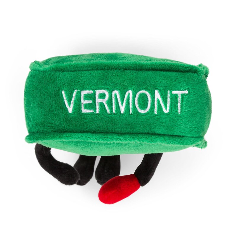 May include: Green plush toy shaped like a Vermont state with the word "VERMONT" embroidered in white on the front. The toy has black legs and red feet.