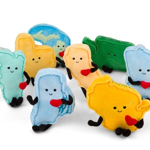 Puede incluir: Colecci&oacute;n de peluches con forma de varios estados de EE. UU. Cada peluche es de un color diferente, con caras sonrientes, brazos y piernas negros y un coraz&oacute;n rojo. Algunos tienen nombres de estados bordados.