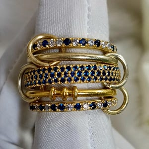 Anel entrelaçado de safira azul e diamantes, com cinco aros interligados em prata 925, ideal para presente de Natal.