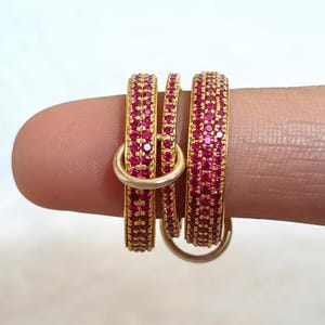 Ring met in elkaar grijpende robijnen en een draaiend element, handgemaakte band van 14-karaats goud met meerdere schakels, een perfect cadeau voor haar.