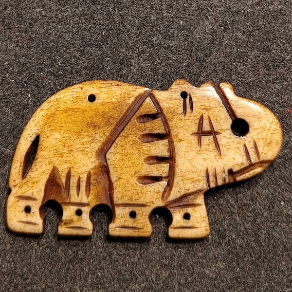 Carved Bovine Bone Elephant. Tan with Brown Accents. 6 Hang Holes 2 on Top 4 on Bottom. Additional Larger Hole at the Trunk Polished Surface
