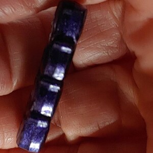 May include: A dark blue, faceted, gemstone pendant with a smooth, polished finish.