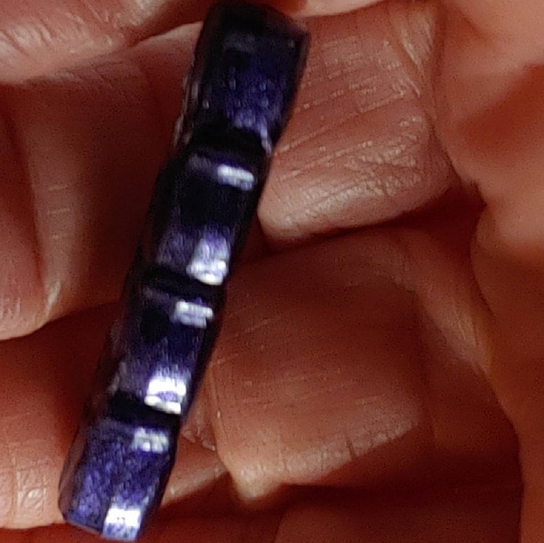 May include: A dark blue, faceted, gemstone pendant with a smooth, polished finish.