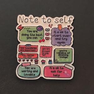 Puede incluir: Un pin de esmalte colorido con las palabras "Note to self". El pin presenta varias burbujas de texto con afirmaciones positivas como "Estás haciendo lo mejor que puedes" y "Eres valioso y amable."