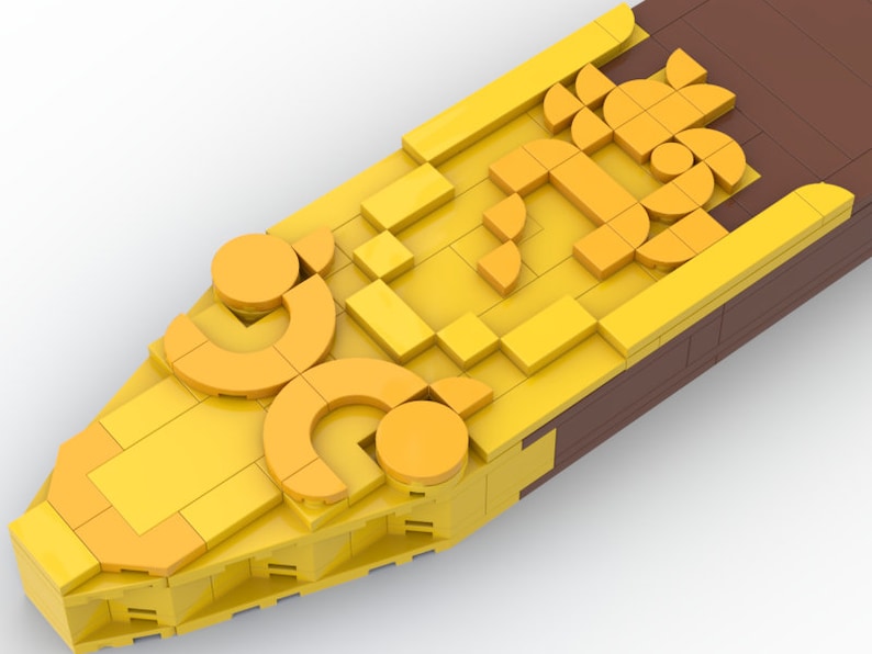 May include: A yellow and brown Lego model of a ship's prow with a decorative design of circles and squares.