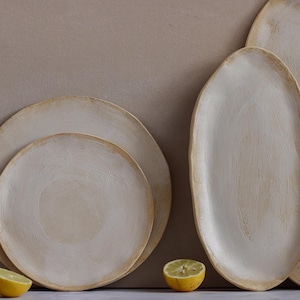 In front of one wall are two plates, a dinner plate and a dessert plate, and two oval platters in matte white glazed stoneware.