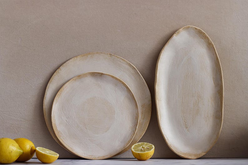 In front of one wall are two plates and an oval platter in matte white glazed stoneware.