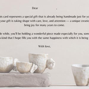 Può includere: Biglietto fatto a mano con il testo "Caro" e "Con amore", sopra e sotto un messaggio su un regalo speciale. Il biglietto è accanto a diverse tazze e ciotole in ceramica dai toni neutri, disposte su una base simile a una pietra.