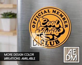 Può includere: Un magnete circolare con sfondo arancione e bordo nero. Il testo OFFICIAL MEMBER è scritto in un arco circolare nella parte superiore, e CLUB in quella inferiore. Al centro, le parole Cool Aunts sono scritte in un font corsivo nero.